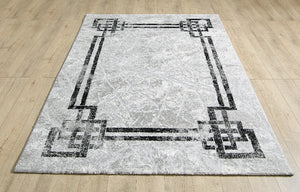 Gray area rug with black geometric patterns on a wooden floor