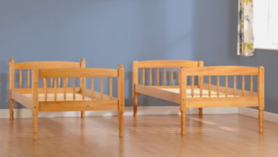 Two wooden children's beds against a blue wall.