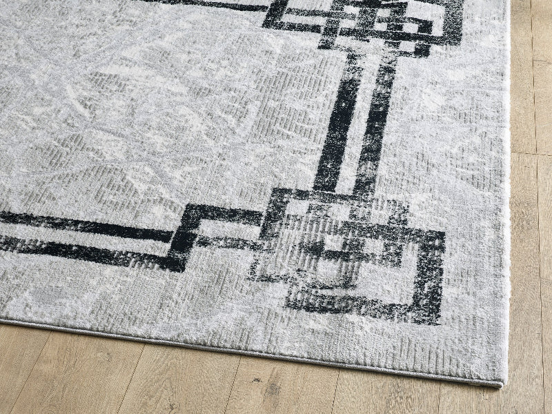 Gray rug with black geometric pattern on a wooden floor