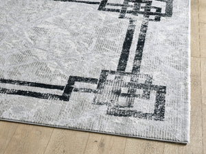 Gray rug with black geometric pattern on a wooden floor