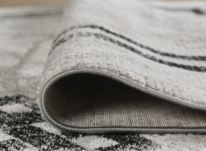 Close-up of a textured gray rug with black stripes on a matching background