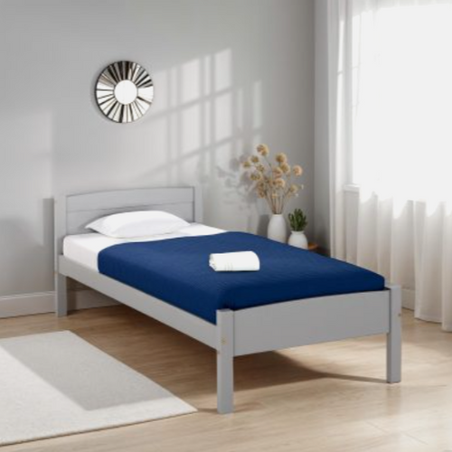 Gray bed frame with blue mattress cover and white pillow in a room with light gray walls and wooden flooring.