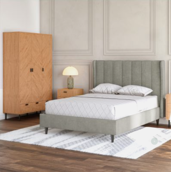 Bedroom with a bed, nightstand, and lamp against a neutral wall.
