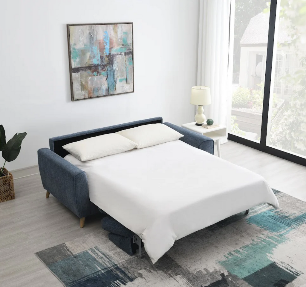 Blue upholstered bed in a modern bedroom with white walls and large windows.