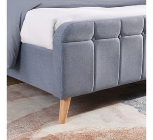 Sky Blue upholstered bed with wooden legs on a patterned rug