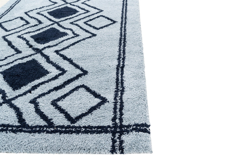Close-up of a blue and black geometric patterned rug on a white background