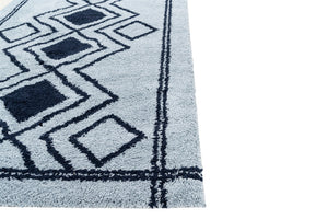 Close-up of a blue and black geometric patterned rug on a white background