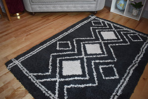 Black and white geometric patterned rug on a wooden floor