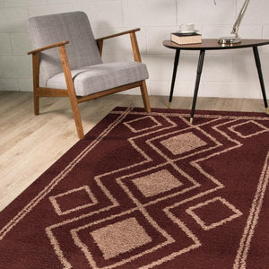 Burgundy geometric patterned rug in a room with a chair and table.