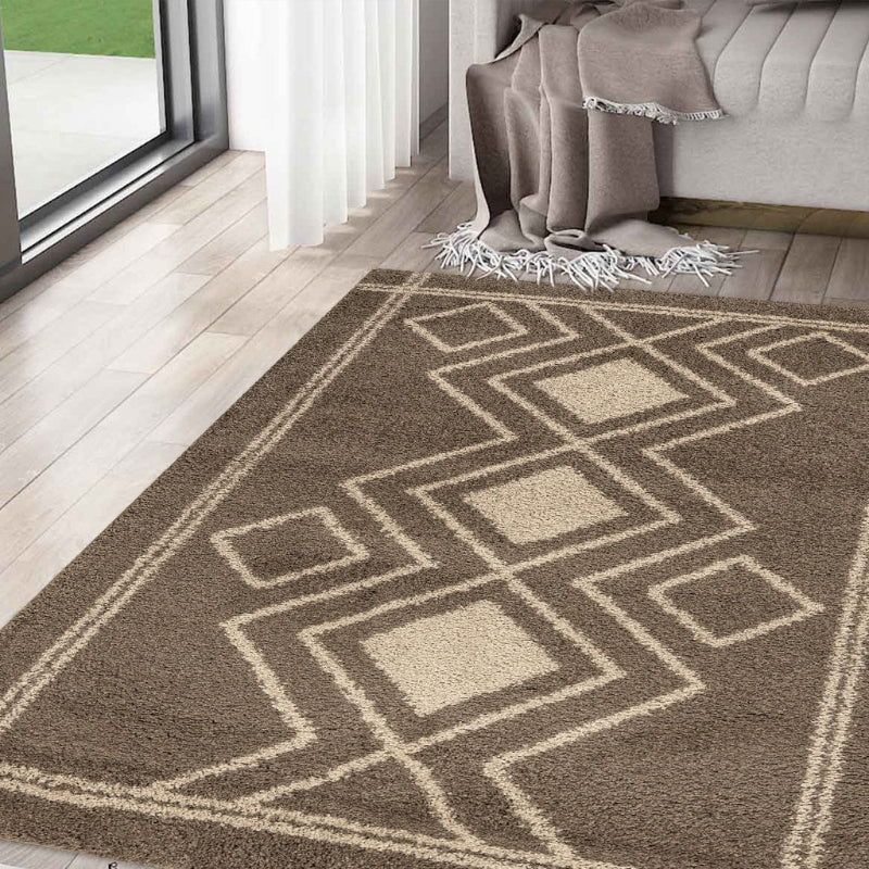 Geometric patterned rug on a wooden floor with a couch and blanket in the background