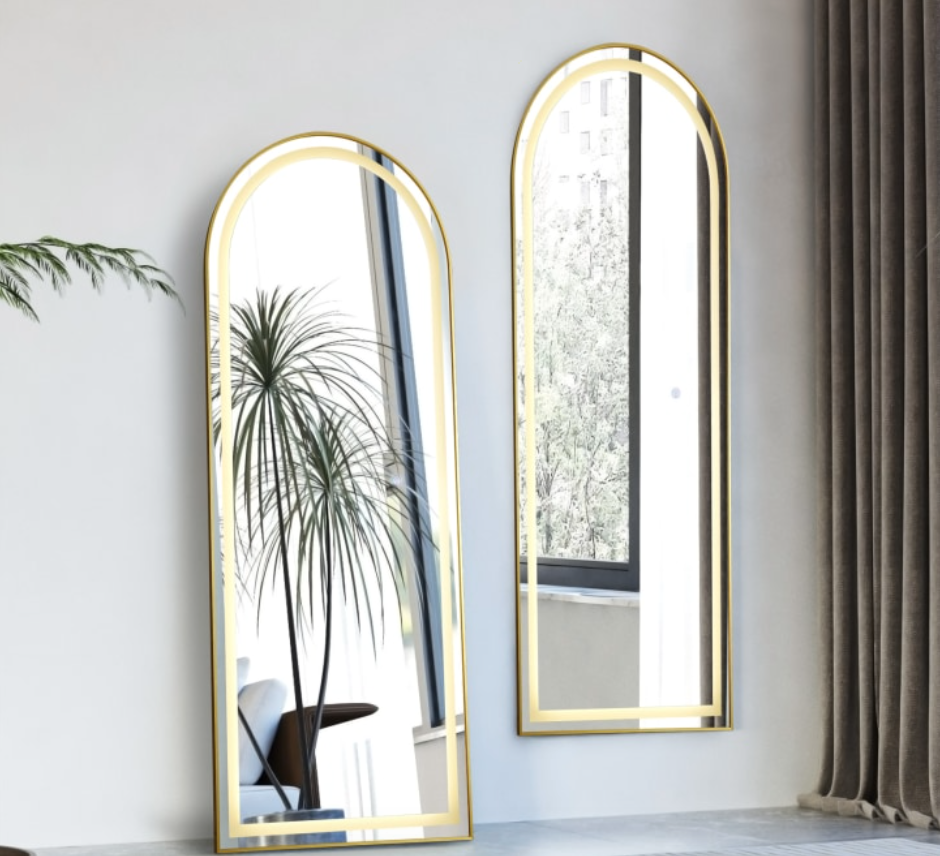 Two arched wall mirrors with gold frames on a light gray wall.