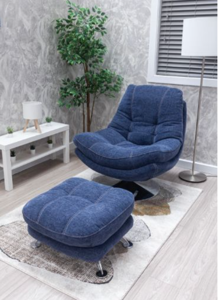 Blue recliner chair with ottoman in a room with a plant and white table.