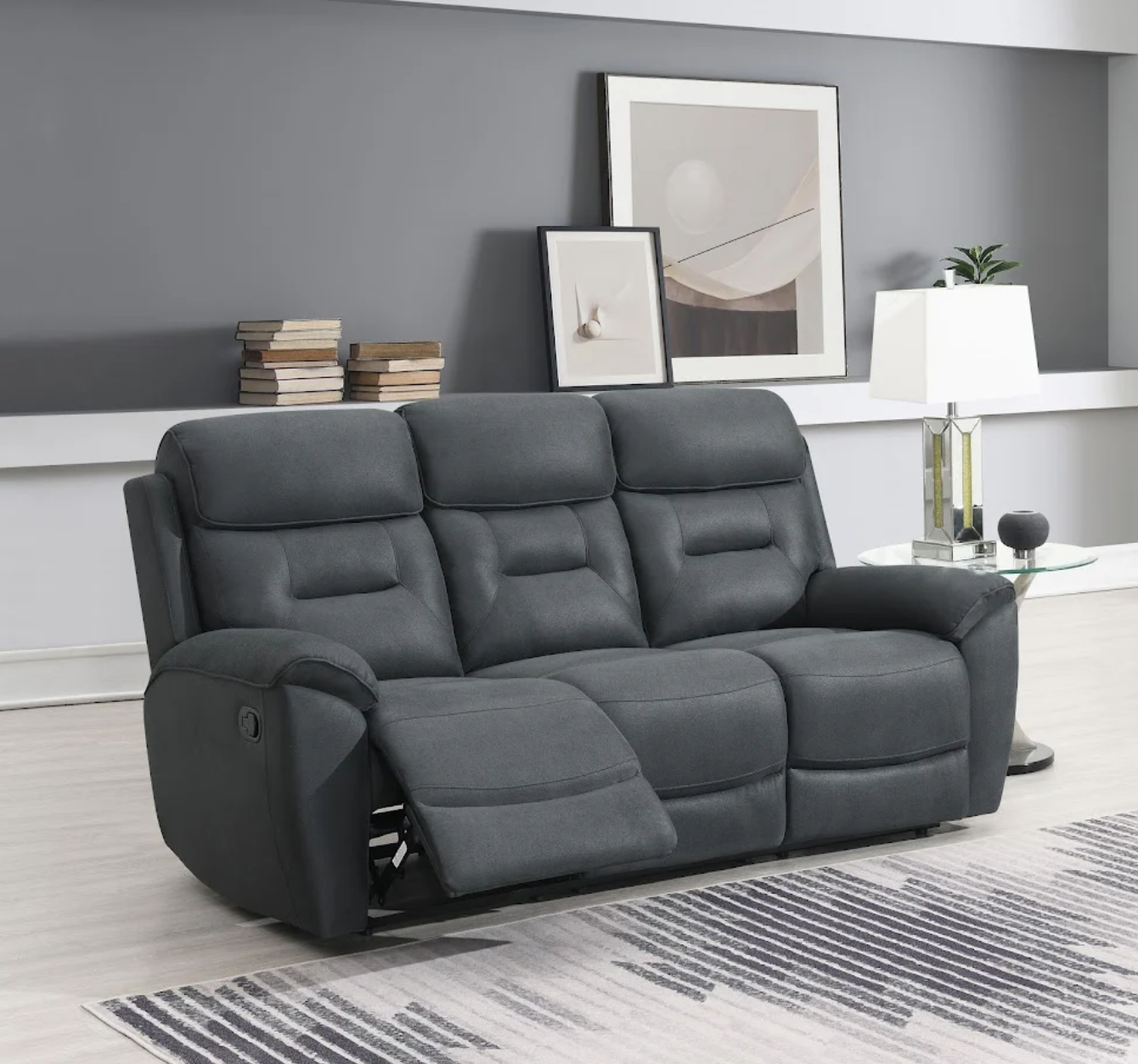 Gray reclining sofa in a living room setting with books and decor.