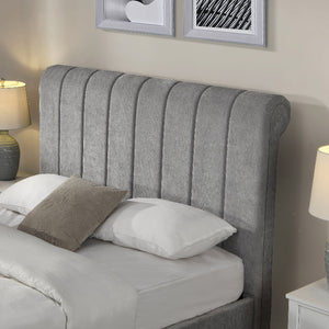 Gray upholstered headboard with pillows on a bed in a bedroom setting.