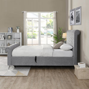 Gray upholstered bed in a bedroom with a window and bookshelf.