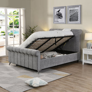 Gray upholstered bed with storage compartment in a room with a window and decor.