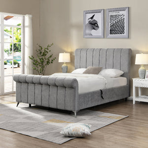 Gray upholstered bed in a well-lit bedroom with decor elements.