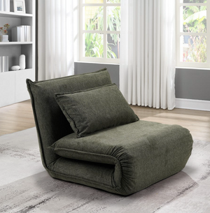 Green floor chair in a room with large windows and a bookshelf.
