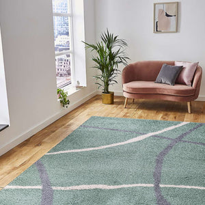 Living room with a pink sofa, green plant, and patterned rug.