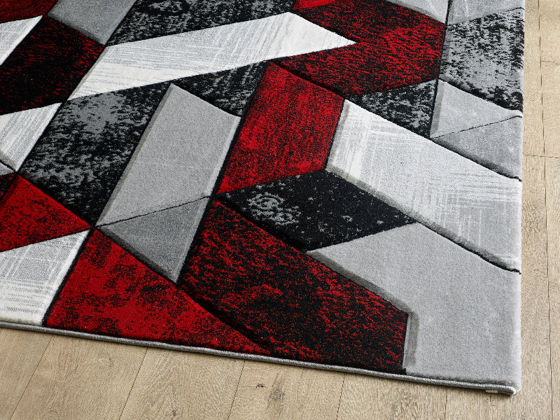 Geometric patterned rug with red, black, and gray colors on a wooden floor.