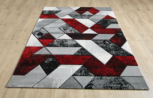 Geometric patterned rug with red, gray, and white colors on a wooden floor.