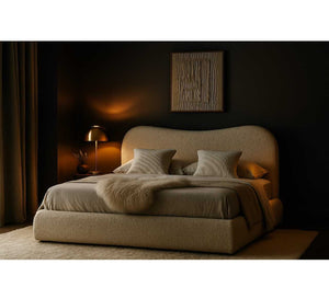 Beige upholstered bed in a dimly lit bedroom with a lamp and abstract painting.