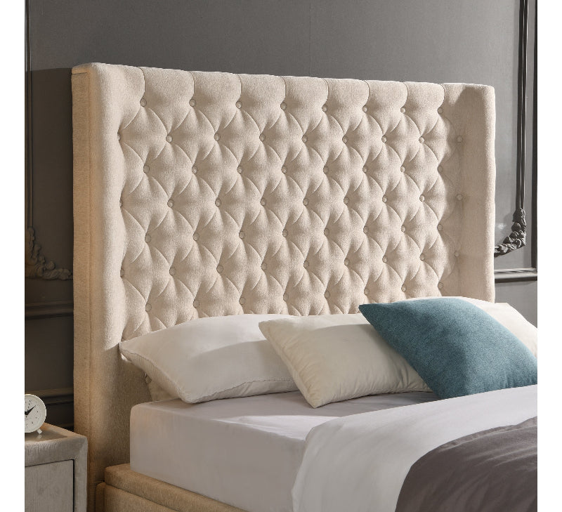 Beige tufted headboard with pillows on a bed in a bedroom setting