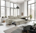 Modern living room with a beige sectional sofa, black coffee table, and large windows.