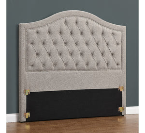 Gray tufted headboard with black base on a gray wall background