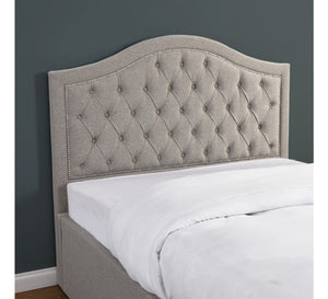 Gray tufted headboard on a bed against a dark gray wall.