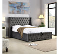 Gray tufted bed in a bedroom with abstract art and lamps.