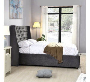 Gray upholstered bed in a bedroom with a large window and decor elements.