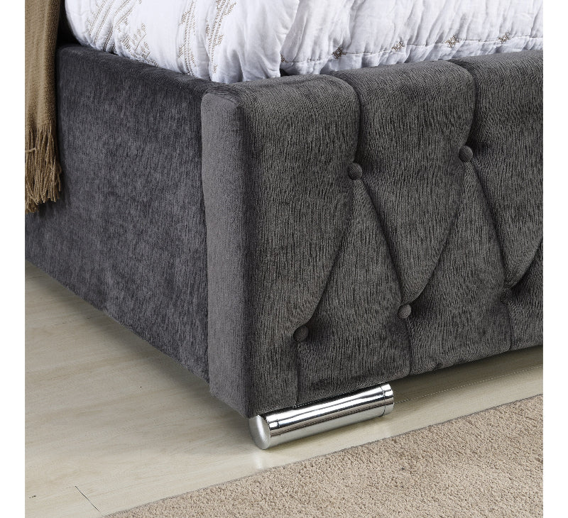 Gray upholstered bed with tufted design on a wooden floor.