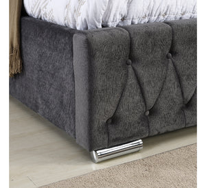 Gray upholstered bed with tufted design on a wooden floor.