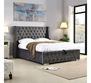 Gray tufted bed in a bedroom with abstract art and lamps.