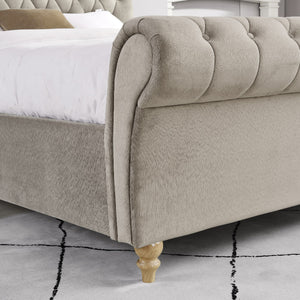 Mink upholstered bed with tufted design and wooden legs on a light gray floor.