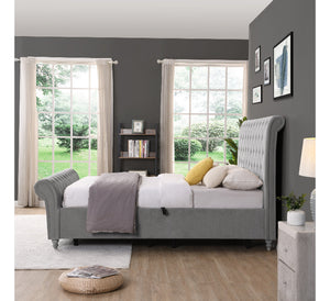 Grey upholstered bed in a bedroom with large windows and grey walls.