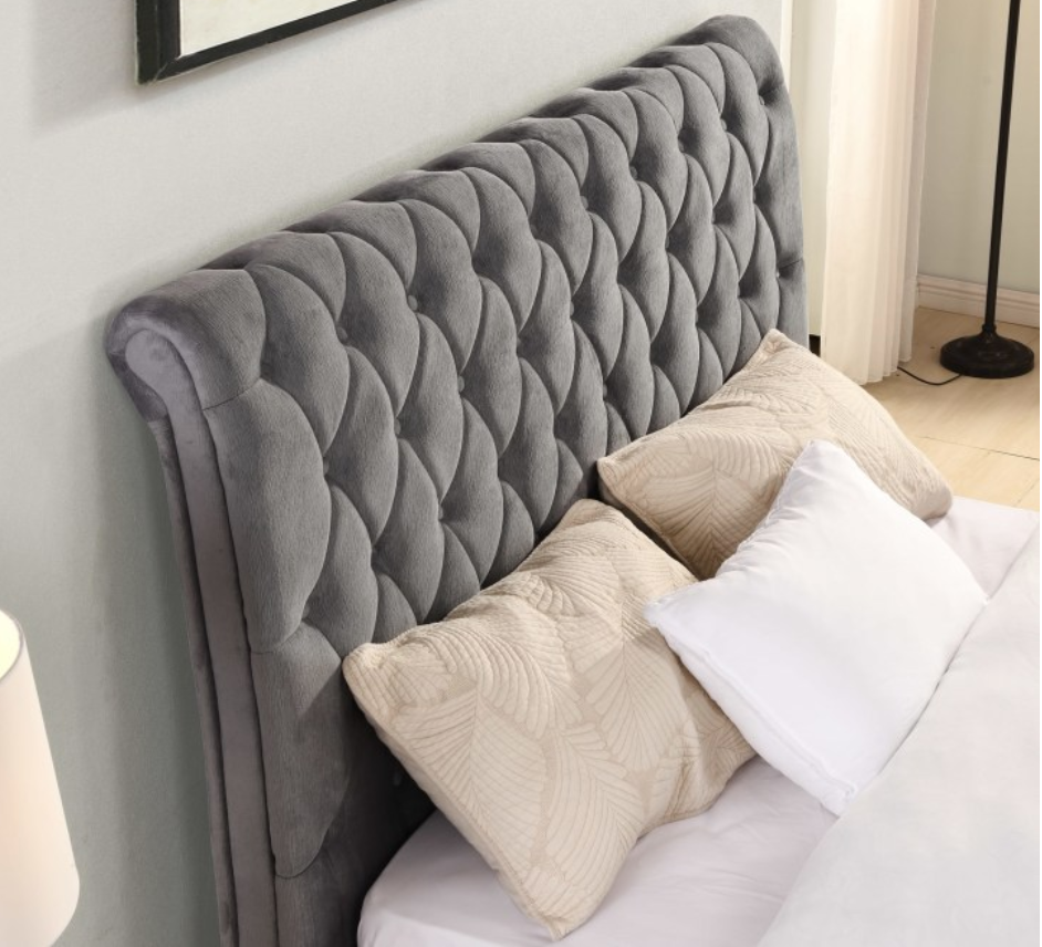Gray tufted headboard with pillows on a bed in a bedroom setting