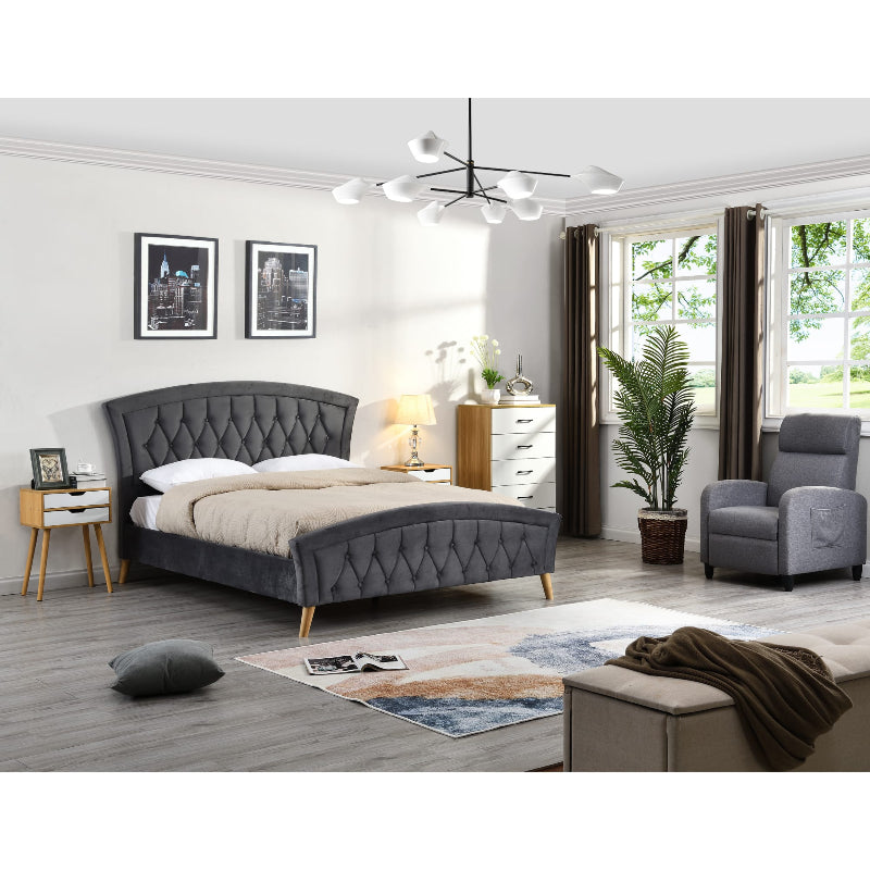 Modern bedroom with grey upholstered bed, armchair, and decor elements.