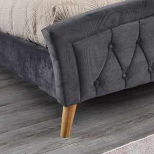 Grey upholstered bed with wooden legs on a wooden floor