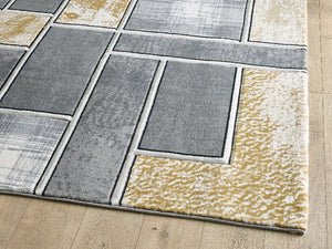 Rectangular rug with a pattern of square tiles in gray, beige, and white on a wooden floor.