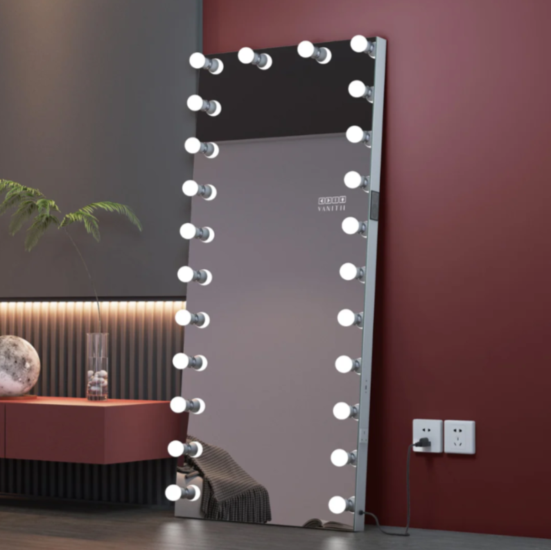 Makeup mirror with lights on a stand against a wall with outlets.