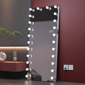Makeup mirror with lights on a stand against a wall with outlets.