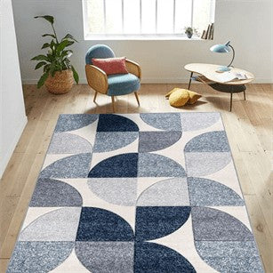 Geometric patterned rug in a room with a chair, table, and plants.
