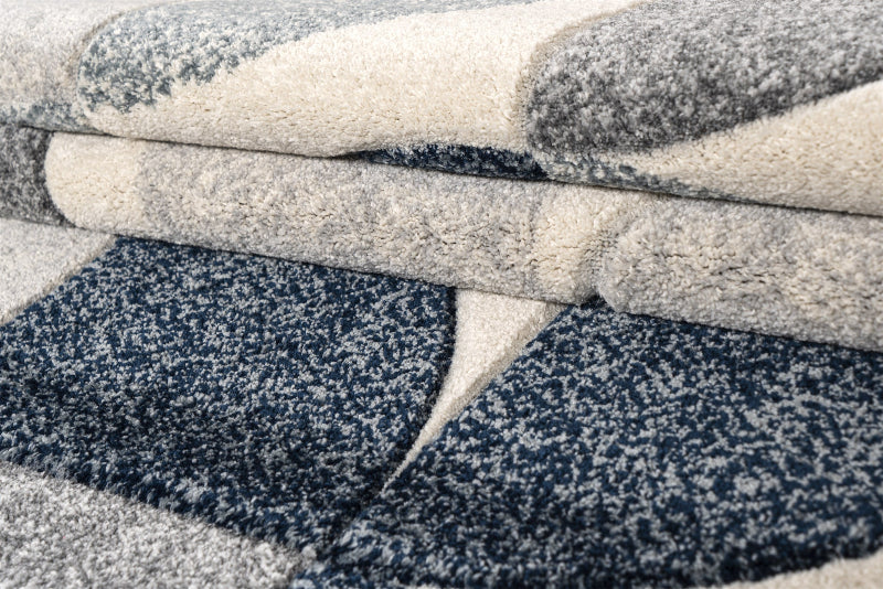 Close-up of textured fabric rolls in gray, beige, and blue.