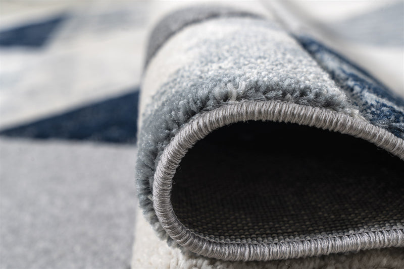 Close-up of a rolled-up gray rug with a striped pattern in the background.