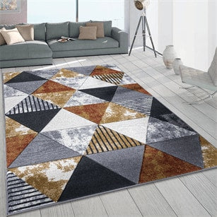 Geometric patterned rug on a wooden floor with a gray sofa and white walls in the background
