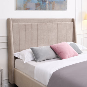 Beige upholstered bed with colorful pillows against a white wall with abstract art.