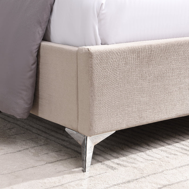 Close-up of a beige upholstered bed frame with a white mattress and gray bedding.