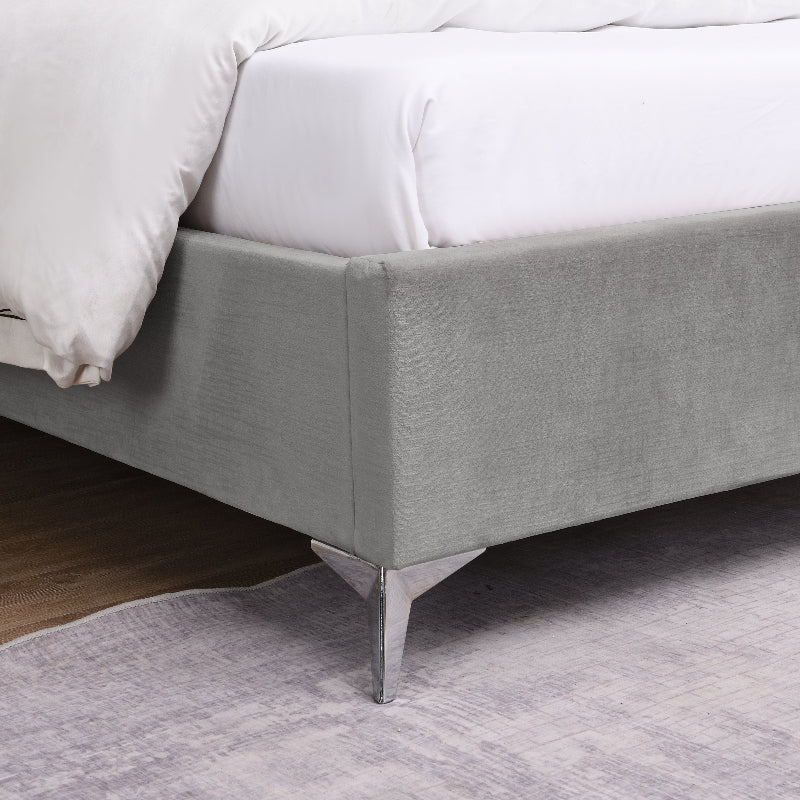 Grey upholstered bed with metal legs on a carpeted floor
